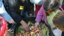 Mains d'enfants et d'un animateur au dessus d'un vermicomposteur rempli d'épluchures