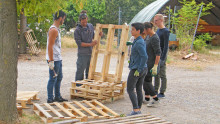 4 agents se forment à la construction d'un fauteuil en palettes