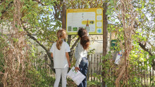 Deux enfants sont devant un panneau dans un jardin