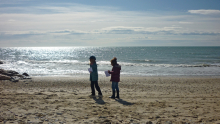 Deux enfants sont sur la plage avec des papiers à la main