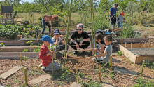 une animatrice et un groupe d'enfant construisent un tipi au jardin pour faire grimper des volubilis