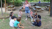une enfant est debout à l'intérieur d'un groupe d'enfants assis et mime la surprise